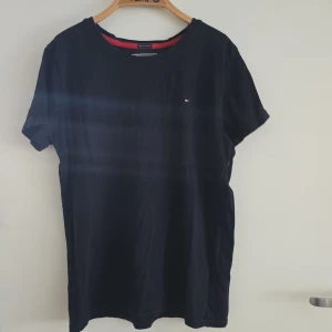 Marinblå t-shirt Tommy Hilfiger, stl 152 - t-shirt från Tommy Hilfiger i ekologisk bomull. Klassisk modell med rund hals och liten broderad logga på bröstet. Har ett par märken (vita streck men ändå fin tycker jag) 