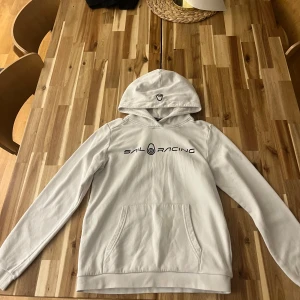 Vit hoodie från Sail Racing - Vit hoodie från Sail Racing med svart logga på bröstet. Perfekt för dig som behöver en höst🍂eller vinter❄️hoodie, kan diskutera pris.