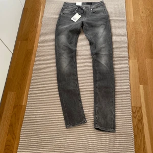 Grå skinny jeans från Tiger of Sweden - Snygga grå jeans från Tiger of Sweden med skinny passform och smal fot. Jeansen har klassisk femficksdesign, diskreta slitningar och är tillverkade i mjuk bomullsdenim. Perfekta för dig som gillar en smal siluett och stilren look. kontakta för info