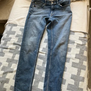 Blå jeans Tiger of Sweden 33/34 - Säljer ett par klassiska blå jeans från Tiger of Sweden, modell Evolve. Jeansen har fem fickor, orangea sömmar och en snygg tvättad look. Passformen är slimfit. Lite slitna där bak upptill som syns på bilden 