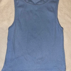 Ribbad topp - Säljer en enkel och stilren blå linnetopp från Cazibe. Toppen är ribbad och ärmlös med rund halsringning, perfekt för en avslappnad look. Materialet är mjukt och stretchigt för extra komfort. Enbart testad