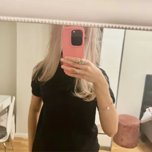 Svart stickad t-shirt från Lindex - Säljer en svart stickad t-shirt från Lindex i storlek S. T-shirten har rund halsringning och korta ärmar, perfekt för en clean och enkel look. Tillverkad i mjukt material som känns skönt mot huden.