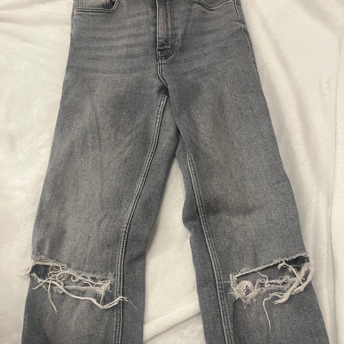 Grå slitna jeans med hål vid knäna