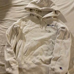 Två Champion hoodies med broderad logga - Säljer två snygga hoodies från Champion, en i vitt och en i olivgrönt. Båda har broderad Champion-logga på bröstet och ärmarna, huva med snörning och stor känguruficka framtill. Perfekta för chill dagar eller när du vill vara extra bekväm.