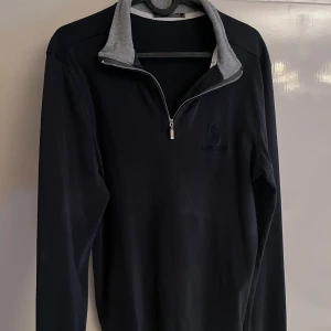  half zip tröja från Ralph Lauren -  långärmad tröja från Ralph Lauren med grå insida på kragen och broderad logga på bröstet. Tröjan har en snygg half zip-dragkedja och är gjord i mjuk bomull. Perfekt för lager-på-lager och chill stil.