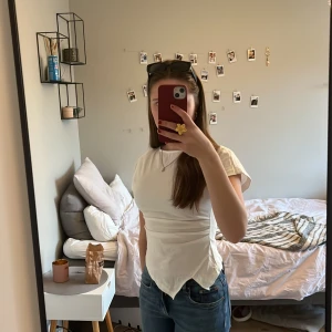 Vit topp med slit - Säljer en vit kortärmad topp från Cider i storlek XS. Toppen har en unik asymmetrisk nederkant och en figurnära passform. Materialet känns mjukt och stretchigt, perfekt till jeans eller kjol. Enkel och stilren design som lyfter din outfit. Toppen är helt nyinköpt och säljer då den var lite för liten. Skriv för fler bilder 💕🙌🏻