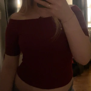 Vinröd offshoulder topp - Säljer en vinröd offshoulder topp med korta ärmar. Toppen är croppad och har en tight passform som sitter snyggt över axlarna. 