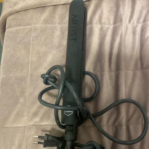 Artist Nordica Plattång - Artist Nordica plattång i svart, med sladd och EU-kontakt. Produkten ser ut att vara i gott skick utan synliga repor eller skador. Perfekt för att styla och räta ut håret snabbt och enkelt. Passar både hemma och på resan.