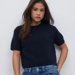 Mörkblå stickad kortärmad tröja - Säljer en mörkblå stickad tröja med korta ärmar och rund hals. Tröjan har en loose passform och är lite croppad, vilket gör den snygg till jeans eller kjol. Tröjan är i storlek 170, men skulle passa de med 158/164.💓💓💓