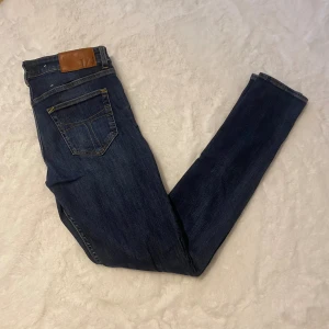Tiger of Sweden mörkblå jeans 30/32 - Mörkblå jeans från Tiger of Sweden med klassisk femficksdesign och snygga kontrastsömmar. Modellen heter Slight och har en rak passform. Jeansen är tillverkade i Italien och har läderpatch med logga bak i midjan. Perfekta för dig som gillar stilrena och tidlösa jeans.