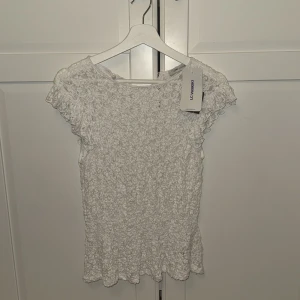 Vit spetsblus från LC Waikiki - Supersöt vit blus med spets och volangärmar från LC Waikiki. Blusen har en lätt struktur, rund halsringning och fina detaljer i spets över hela plagget. Perfekt för dig som gillar romantisk och feminin stil.