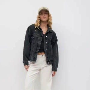 Oversized svart jeansjacka - Säljer en oversized svart jeansjacka med klassisk krage, bröstfickor med knappar och silvriga detaljer. Jackan har långa ärmar och en loose fit som ger en chill vibe. Perfekt att slänga över en hoodie eller crop top.