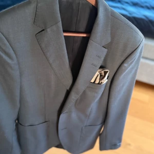 Svart kavaj från Tiger of Sweden inkl byxor  - Stilren svart kavaj från Tiger of Sweden med klassisk passform och snygga detaljer. Kavajen har två framfickor, bröstficka med näsduk och knappar vid ärmslut. Perfekt för dig som vill ha en tidlös och elegant look. Original pris = 5500 kr 