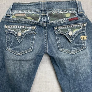 Miss Me jeans med camouflage - Snygga blå jeans från Miss Me med camouflage-detaljer på fickorna, nitar och strass. Jeansen har bootcut-modell och är special edition. Storlek S, ge gärna prisförslag💞