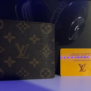 Monogram Plånbok - Snygg plånbok från L—V med klassiskt monogrammönster i brunt och beige. Plånboken har flera kortfack, myntficka med lock och är tillverkad i exklusivt skinn. Perfekt accessoar för dig som gillar lyxiga detaljer och stilren design.