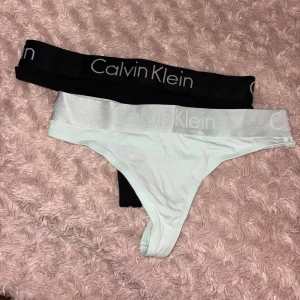 Calvin Klein stringtrosor 2-pack S - Två par Calvin Klein stringtrosor i storlek S. Ena paret är svart med bred resår och logga, det andra är ljus mintgrön med glansig silverresår och logga. Båda är i mjuk bomullsblandning och har klassisk Calvin Klein-design. Aldrig använda. Saknar dock lapp då det va ett tre-pack och endast ett par är provade (de som inte säljs). 