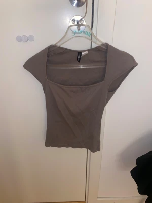 Beige/grön ribbad topp från Divided - Säljer en beige/grön ribbad topp från H&M Divided med fyrkantig halsringning och breda axlar. Modellen är ärmlös och har en slim passform som sitter snyggt mot kroppen. Perfekt att styla med jeans eller kjol för en chill look.