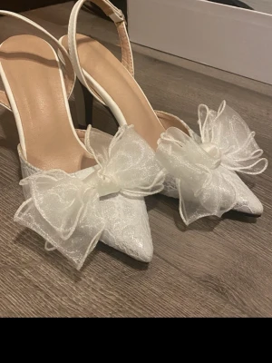 Vita klackskor med rosett  - Vita stiletto klackskor med rosett och öppen häl. Endast testade 