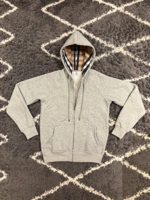 B zip hoodie - Grå  hoodie med ikonisk rutig insida i huven och diskret broderad knight-logo. Oanvänd med alla taggar kvar. Storlek S lotten i storlek. Liten i storlek.