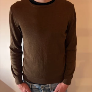 Brun stickad tröja från Bläck - Snygg brun stickad tröja från Bläck i storlek M. Tröjan har rund halsringning och långa ärmar, perfekt för lager-på-lager. Materialet är mjukt och skönt, och den neutrala färgen gör den enkel att matcha med jeans.