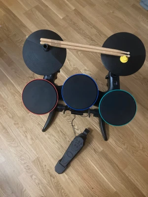 Bandhero trumset  endast Xbox 360 kompatibel  - Trumset  till badhero fint skick sällan använts  endast kompatibel med Bandhero ” Ej guitar hero ”  diverse kablar medföljer ej förutom trumpedalen .  . Om inte gratis frakt erbjuds så inkluderas detta i priset efter kontroll av frakt @ Story paket . 