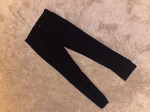 Svarta kostymbyxor från C - Snygga svarta kostymbyxor från C i storlek 146/11 yrs. Byxorna har klassisk rak passform med knapp och dragkedja framtill. Perfekta för en stilren look och passar till skjorta eller t-shirt.