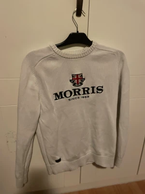 Vit Morris tröja med tryck  - Säljer en vit stickad tröja från Morris med tryck. Tröjan har rund hals, ribbade muddar och lång ärm. Perfekt för dig som gillar klassisk stil med en modern twist. Ett perfekt plagg som letar efter en skön tröja för de kyligare säsonger🤩