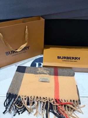 Burberry beige scarf -Unisex - Snygg rutig väst från Burberry i 100% kashmir. Klassisk beige, svart och röd färg med fransar nedtill och broderad Burberry-logga på bröstet. Perfekt för dig som vill ha en lyxig och tidlös look med ikoniskt mönster.