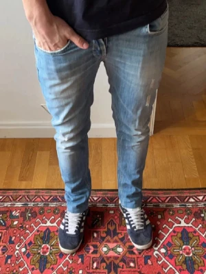 Ljusblå slim jeans från Dondup - Säljer ett par dondup jeans med slitningar på framsidan. De har en slim passform och är i storlek 33. Perfekta för en avslappnad stil och perfekta inför vardagen. Stilrena och sköna! Hör av er vid minsta fundering!