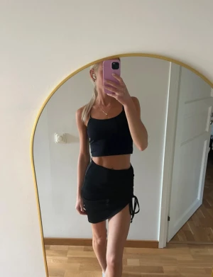 Svart kortkjol med snörning - Svart kortkjol med justerbar snörning på sidan. Kjolen har tyvärr aldrig kommit till användning av mig så helt ny (endast testad). Ifrån NA-KD & i storlek XXS🖤 