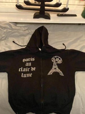 Bling lucid  - En snygg svart zip hoodie med snygga detaljer har typ små blånkande pluppar som märke 