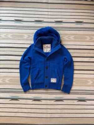 Blå cardigan från hollister - Riktigt snygg o varm jacka perfekt inför vinter/våren. Använd men utan defekter!