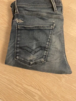 Mörkblå Replay Anbass jeans - Snygga mörkblå Replay Anbass jeans med klassisk femficksdesign och diskreta slitningar. Jeansen har smal passform och är tillverkade i stretchigt denim för extra komfort. Perfekta för dig som gillar en modern och stilren look.