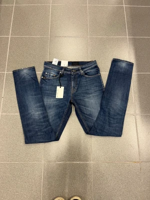 Blå tiger of sweden jeans W29 L34 - Snygga blå jeans från Tiger of sweden jeans med  klassisk straight fit med smal fot. Jeansen har fem fickor, orange kontrastsömmar och en mörk läderpatch bak i midjan. Perfekt passform för dig som gillar raka ben och stilren look.