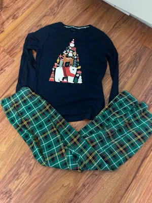 Mörkblå jultröja med print från Esmara - Mörkblå långärmad tröja från Esmara med juligt print framtill som visar en snögubbe, ren och isbjörn i färgglada detaljer. Rund hals med grön och rutig kant. Tröjan är gjord i mjuk bomull och har en normal passform, perfekt för att maxa julkänslan.