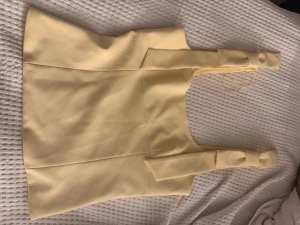 Gul omlott topp med rosett från Zara - Snygg ljusgul omlott topp från Zara med breda axelband och rosett-detaljer på axlarna. Använd 1 gång💕