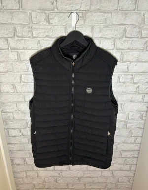 Stone Island väst - Stone Island väst i klassisk svart färg. Tidlös och stilren väst som passar perfekt för lager-på-lager året runt. Använd men i överlag bra skick. Dragkedjan saknar själva dragdelen, går enkelt att ersätta med ny metall-dragdel eller byta helt vid behov. I övrigt fint helhetsintryck. Hör av dig vid intresse 🙌