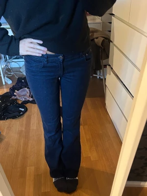 Mörkblå bootcut jeans - Snygga mörkblå jeans med klassisk femficksdesign och bootcut-ben. Jeansen har låg midja och är tillverkade i ett stretchigt denimtyg som sitter skönt och formar sig efter kroppen. Perfekta för dig som gillar en tidlös och cool look. 83 är innebenslängden, jag är 172!