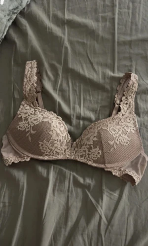 Beige spetsmönstrad bh från Intimissimi  - Priset går att diskuteras!!! Säljer en gammelrosa bh från Intimissimi med vacker spets och blommigt mönster över kuporna och axelbanden. Bh:n har lätt vaddering och ger snygg form. Perfekt för dig som gillar romantiska detaljer och mjuka material.