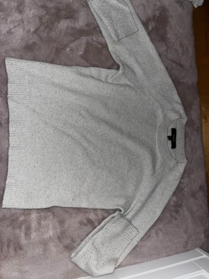 Ljusgrå stickad tröja från Vero Moda - Supermysig vit stickad tröja från Vero Moda i storlek S. Tröjan har ribbade muddar vid ärmslut och nederkant, rund halsringning och en klassisk, enkel design som är lätt att matcha. 