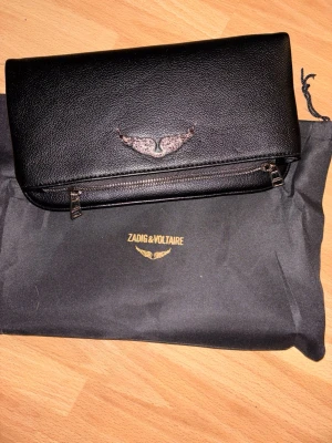 Svart och SILVRIG Zadig & Voltaire - Stilren svart kuvertväska från Zadig & Voltaire i skinn med silverfärgad dragkedja. För fler bilder skriv gärna. Den har inga tecken på användning.