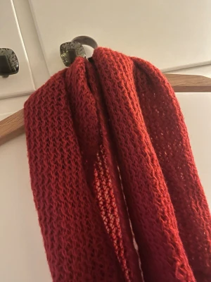 Röd stickad halsduk  - Säljer en röd stickad halsduk med grov meshstruktur och loose fit. Väldigt mysig och fin. Perfekt för dig som gillar chill och avslappnad stil.