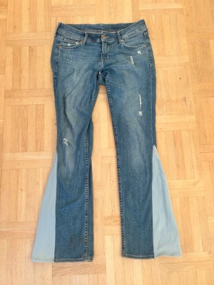 Blå bootcut jeans med ljusa kilar💖 - Unika blå jeans med bootcut-modell och ljusa tygkilar på utsidan av benen. Klassisk femficksdesign, slitna detaljer och knappgylf. Jeansen har en cool retrovibe och är tillverkade i bomull med denimkänsla. Perfekta för dig som vill sticka ut med din stil.