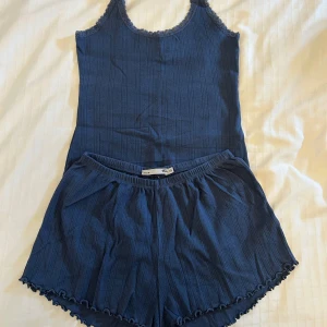 Mörkblå pyjamas /loungeset från lager 157 - Mörkblå pyjamas/loungeset från lager 157 i storlek XS. Setet är i ribbad bomull med randigt mönster. Shortsen har elastisk midja och volangkant längs bensluten och toppen har spetsband. 