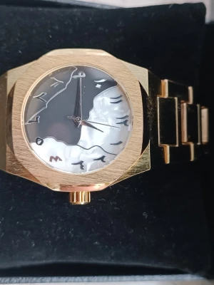 Guldklocka med "Arabic Dial" - Säljer en riktigt fet guldklocka med den eftertraktade "Arabic Dial"-designen (öst-arabiska siffror). Urtavlan är unik med en tvådelad design: mattsvart på ena sidan och en pärlemor/marmor-liknande effekt på den andra.