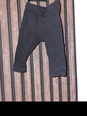 Svarta leggings i storlek 62 - Ett par svarta leggings i mjukt bomullsmaterial. De har en enkel och clean design med resår i midjan och smal passform. Perfekta att matcha med oversized tröja eller hoodie för en chill look. Storlek 62