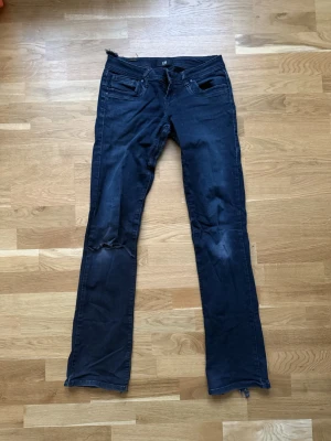 Low waist jeans från LTB med slitningar - Säljer ett par jeans från LTB, dom är svarta men lite urtvättade i färgen. Jeansen har ett hål i ena knät och har tyvärr spruckit i innerlåren men en skräddare har sytt ihop det så det är inget som syns. Storlek 25/34