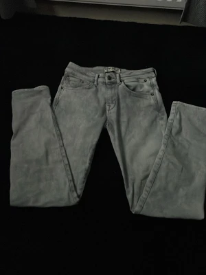 Grå raka jeansbyxor - Säljer ett par grå jeansbyxor med klassisk femficksdesign och raka ben. Byxorna har bälteshällor och metallknapp i midjan. Perfekta till en avslappnad stil och passar till det mesta.