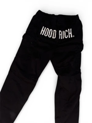 Svarta byxor från Hoodrich - Svarta byxor från Hoodrich med vit logotyp på benet och bak, samt röda detaljer på fickorna. Byxorna har elastisk midja och flera praktiska fickor. Perfekt för dig som gillar streetwear och vill ha en cool look.