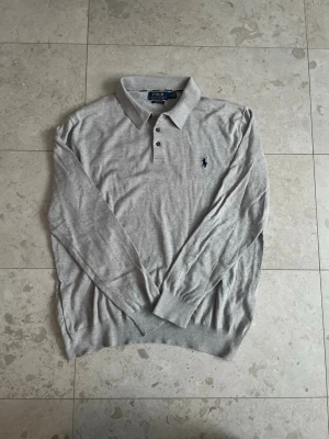 Ralph Lauren Rugby tröja (Långärmad Polo)  - Säljer den här galet feta Rugby tröjan från Ralph lauren, eftersom att den har blivit för liten för mig. Snygg grå färg, med stilrena knappar och krage! || Skick: 8.3/10 || Storlek: L, passar även M bra! || Hör gärna av dig vid frågor, funderingar eller prisförslag!😄